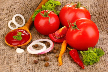 Ketchup and ripe tomatoes on sacking close-up