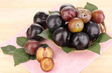 Rip plums on basket on wooden table