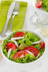 vegetable salad in white bowl with fork and knife