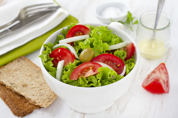 vegetable salad in white bowl with fork and knife
