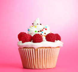 tasty cupcake with berries, on pink background