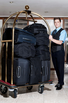 Concierge With A Pile Of Bags In Luggage Cart