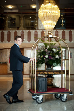 Handsome concierge pushing the luggage cart