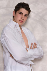 Man wearing white shirt. Handsome young man stands against a gray wall.