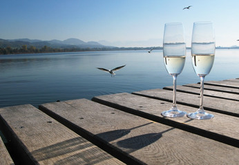 Two champagne glasses against a lake