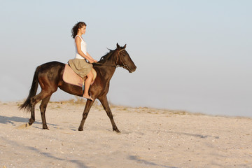 young happy woman riding horse on natural background