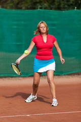 Young woman playing tennis on a dross field