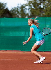 Young woman playing tennis on a dross field