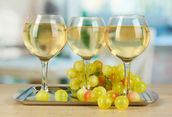 White wine in glass on salver on room background