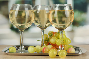 White wine in glass on salver on window background