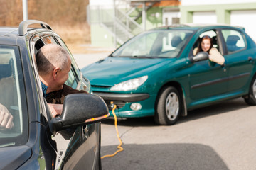 Man helping woman by pulling her car