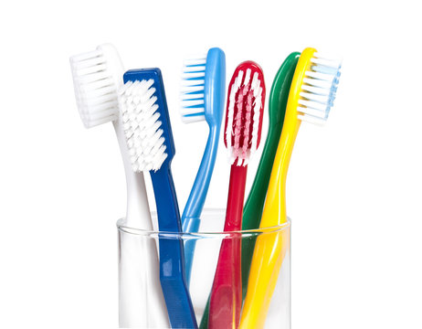 colorful toothbrushes in a glass over white