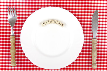 White plate with Dinner-lettering and wooden cutlery