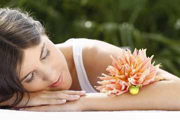 Obraz na płótnie Canvas Brunette kobieta z kwiatem podczas relaksu