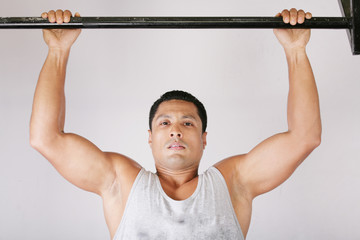 Naklejka premium Athlete pull oneself up on gym background