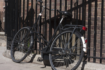 Fototapeta na wymiar Old black bicycle against railings