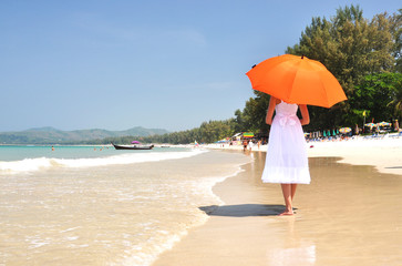 Girl with an orange umbrella on the sandy beach