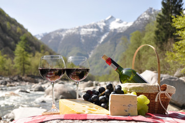 Red wine, cheese and grapes served at a picnic. Verzasca valley,
