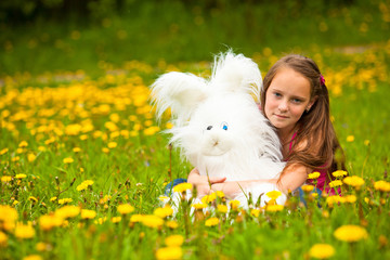 Young little girl holding a soft toy in the park.