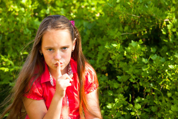 Little girl with her finger over her mouth, hushing.