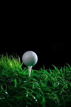 golf ball on green grass with black background