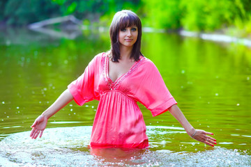 brunette woman model red dress is wet to waist in water touches