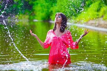 Fototapeta premium woman model in a red dress is standing in the rain to the waist