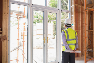 Architect holding a plan while looking outside