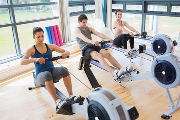 Fototapeta premium Three people on rowing machines