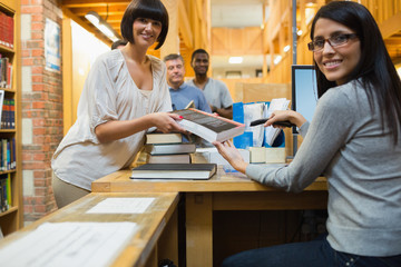 Librarian scanning book and handing to woman