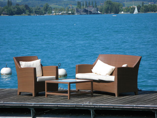 Two armcairs on a wooden deck against water. Lake Thun, Switzerl