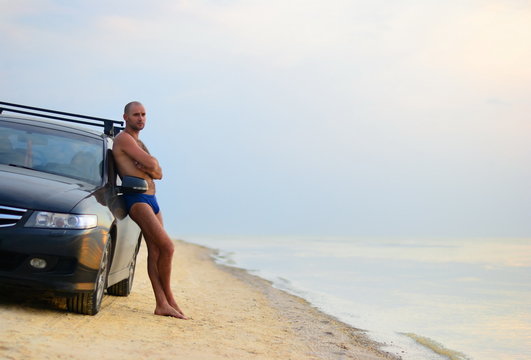 Man Near The Car On A Sandy Beach