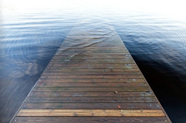Perspective of an old wooden pier goes under deep blue water