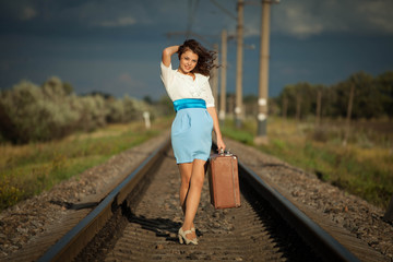 Young fashion girl with suitcase at railways.