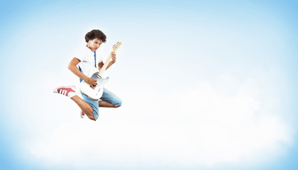 young man playing on electro guitar and jumping