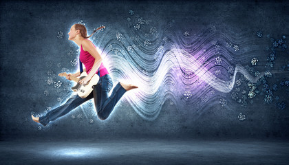 young woman playing on electro guitar and jumping