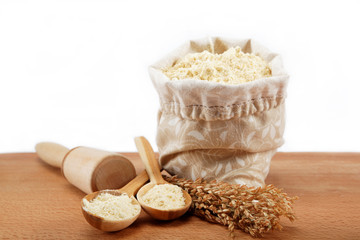 Corn flour in a bag with wooden spoon and ear on wooden table.