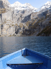 Prow of a boat against surface of Oeschinensee lake and snowy Al