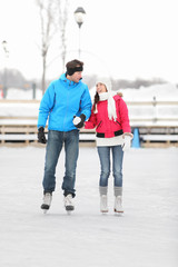 Young couple ice skating outdoors