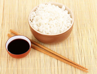 Bowl of rice and chopsticks on bamboo mat