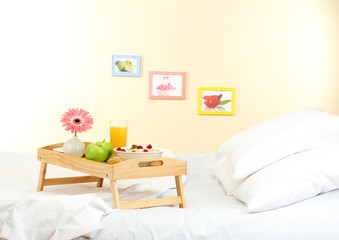 wooden tray with light breakfast on bed