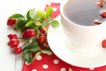 Obraz na płótnie Canvas cup of tea with hip roses, on wooden table