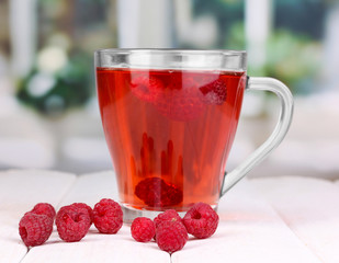 tea with raspberries on table on bright background
