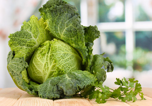 Fresh savoy cabbage on wooden table on window background
