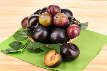 Rip plums on basket on wooden table