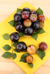 Rip plums on basket on wooden table