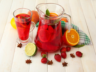 sangria in jar and glass with fruits, on white wooden table