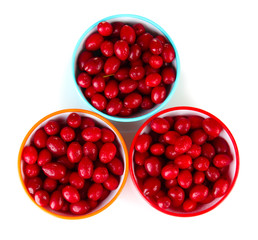 fresh cornel berries in colorful bowls isolated on white