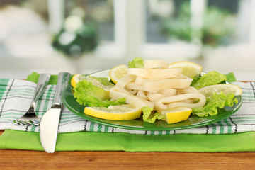 cooked squid rings on lettuce with lemon on the plate close-up