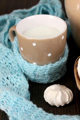 Pitcher and cup of milk with meringues on wooden table close-up